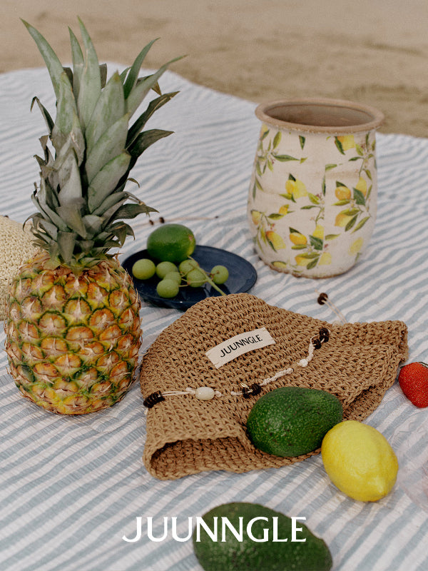 Fruit and woven bag on a striped tablecloth with 'JUUNGGLE' branding.